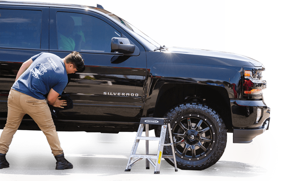 self-service car wash. a man in a work jumpsuit wipes the car dry after washing